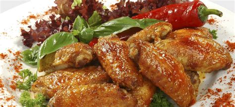 Plato con diversas alitas de pollo preparadas de diferentes maneras, con salsas variadas y guarniciones