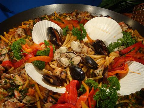 Fotografía de ingredientes frescos: tomates, pimientos, ajos, perejil y pescado, listos para ser usados en la cazuela.