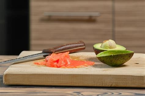 Tabla de cortar con salmón ahumado, aguacate y otros ingredientes frescos para recetas keto.