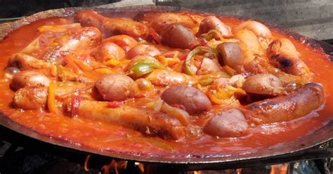 Chorizo a la pomarola cocinándose en un disco de arado