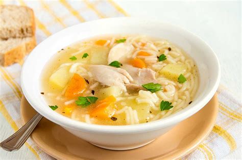 Foto del plato de caldo de pollo servido en un cuenco, decorado con hierbas frescas.