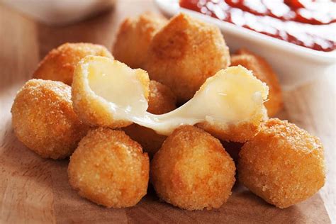 Bolitas de queso azul rebozadas en frutos secos sobre una cuchara de presentación