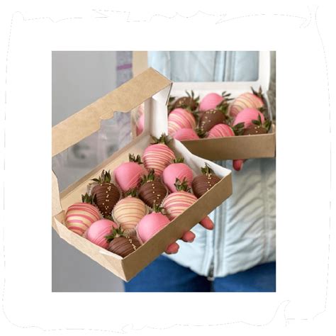 Fotografía profesional de fresas bañadas en chocolate con decoraciones de chocolate blanco y frutos secos sobre papel de horno.