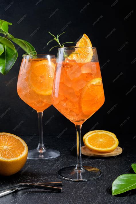 Cóctel Atardecer en vaso de Spritz con rodaja de naranja y puesta de sol de fondo