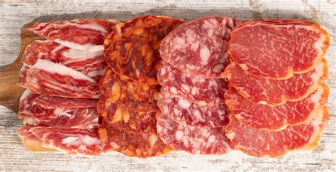 Muestra de embutidos ibéricos variados, incluyendo lomo, salchichón, chorizo y jamón