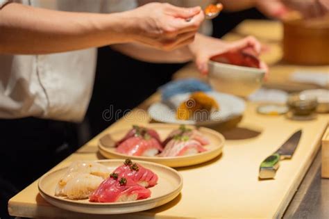 Ayudante de sushi preparando ingredientes frescos en una cocina profesional