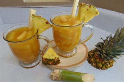 Foto de un vaso de ponche de piña cremoso con un trozo de piña y sombrilla decorativa