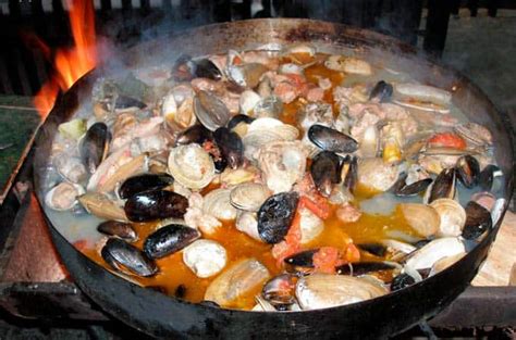 fotografía de un disco de arado con diversos mariscos y carnes cocinándose