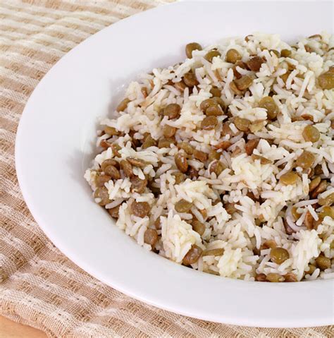 Foto de recipiente de vidrio con arroz y lentejas, con una vela amarilla encendida al lado