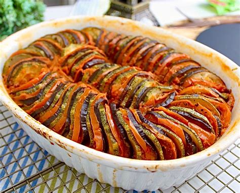 Ratatouille en capas horneado en una fuente, con albahaca fresca de decoración.