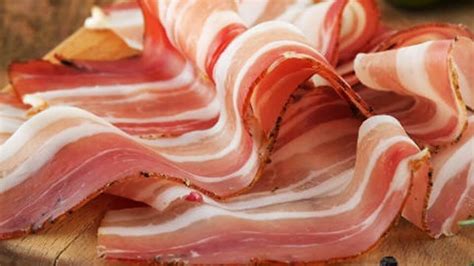 Fotografía de tocino cocido a la perfección con este método, crujiente y dorado, sobre papel absorbente.