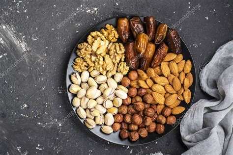 Primer plano de un surtido de frutos secos (almendras, pistachos, piñones) y un cuenco con miel dorada.