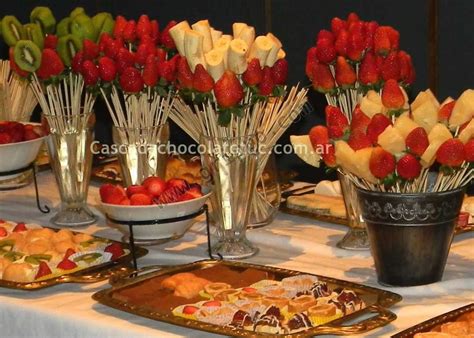 Mesa de degustación con una cascada de chocolate, frutas frescas cortadas, galletas y malvaviscos.