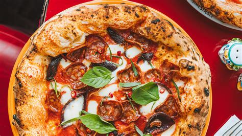 Selección de pizzas artesanales de Pizzeria Olympia servidas sobre mesa de madera.