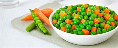 Plato con diversos vegetales cocidos como espinacas, guisantes y zanahorias, adecuados para alimentar caracoles manzana