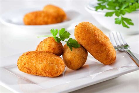 Imagen de croquetas siendo rebozadas en huevo y pan rallado.