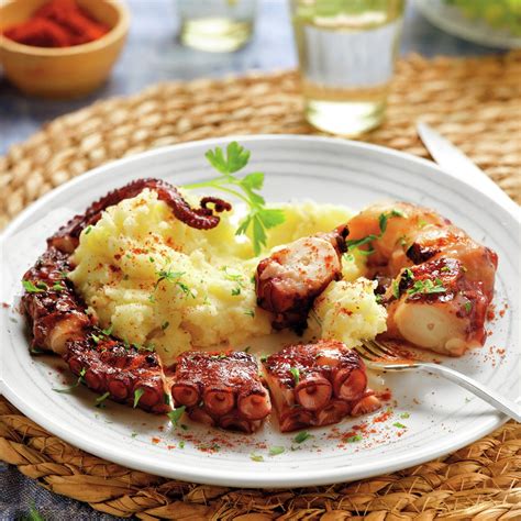 Plato de pulpo a la parrilla con patatas fritas y salsa.