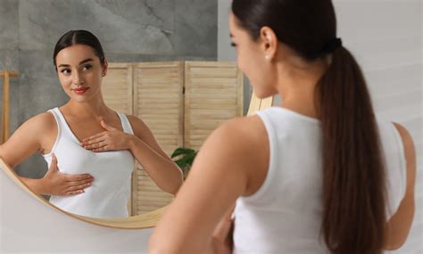 Mujer realizando un autoexamen mamario frente a un espejo