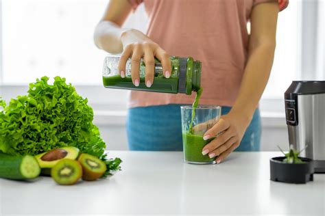 Persona preparando un jugo verde en una licuadora con verduras frescas