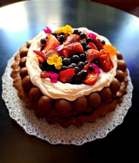 Fotografía profesional de una torta de merengue decorada con diversos dulces, golosinas y frutas frescas.
