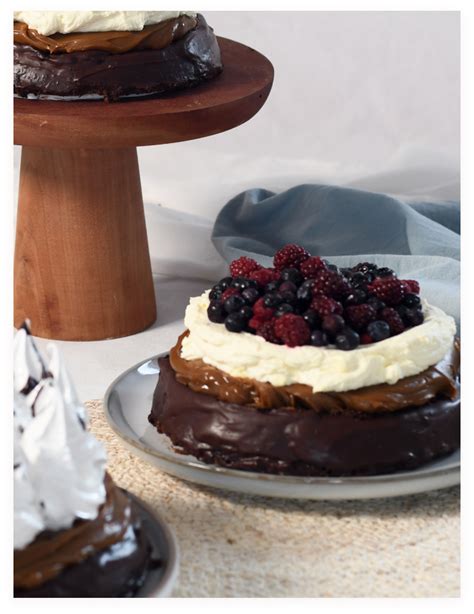 Brownie servido en un plato con frutos rojos y crema batida