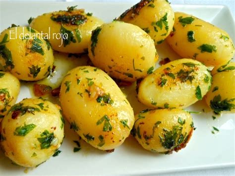 Plato de patatas cocidas con mayonesa de ajo y albahaca, decorado con perejil fresco.