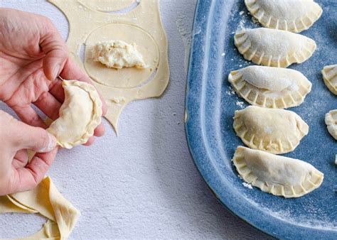 Manos formando empanadas de queso, sellando los bordes con un tenedor