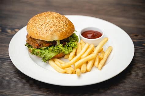 Imagen de una hamburguesa de pollo al estilo venezolano, con papas fritas y salsas, en un plato.