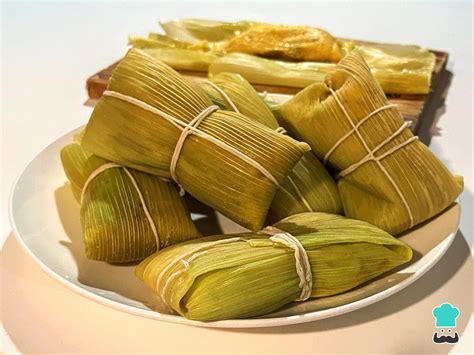 Foto de humitas chilenas recién cocidas listas para servir, acompañadas de ensalada de tomate