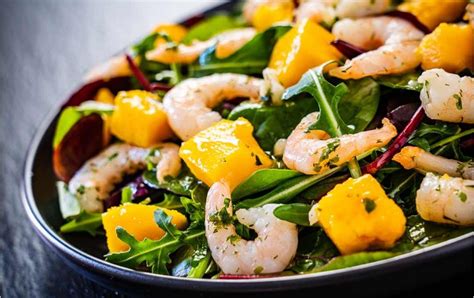 Foto de ensalada de papaya, mango y langostinos recién preparada en un bol