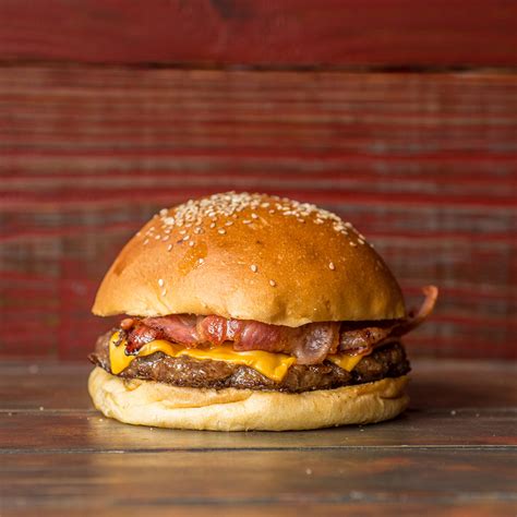Fotografía de una hamburguesa clásica con queso cheddar y panceta, acompañada de papas fritas