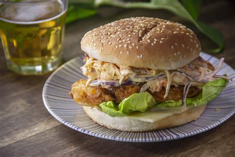 Hamburguesa de pollo frito de estilo caribeño con ensalada de col y especias, en un ambiente tropical