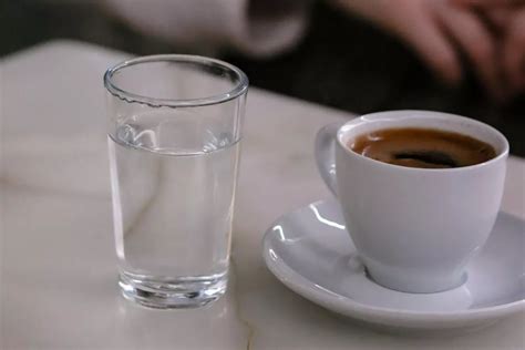 Vaso de agua natural junto a una taza de café espresso