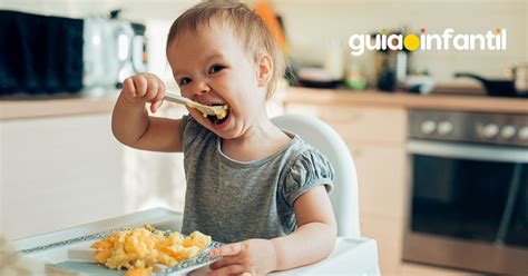 Niño de dos años comiendo de forma independiente en la mesa, foto temática