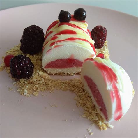 Mousse de chocolate blanco decorada con frutos rojos y hojas de menta