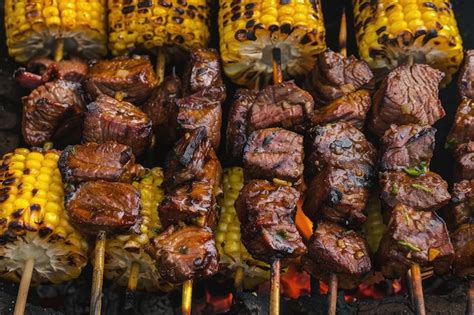 Fotografía de anticuchos de corazón en la parrilla con papas y choclo