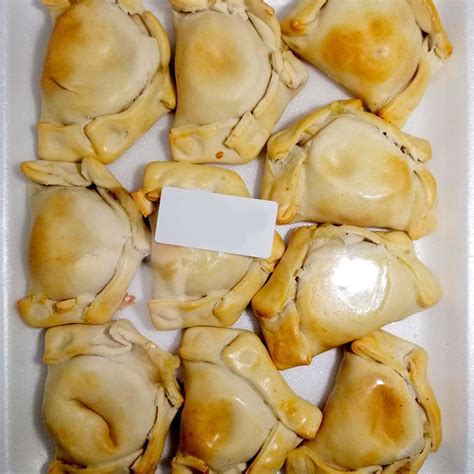 Fotografía profesional de una bandeja surtida de empanaditas de coctel artesanales recién horneadas.