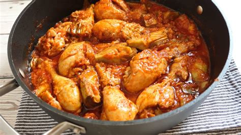Plato de muslos de pollo con tomate y alcachofas servido
