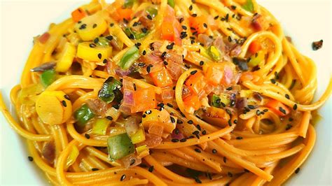 Plato de pasta o fideos con leche de coco y curry, decorado con hierbas frescas y maní