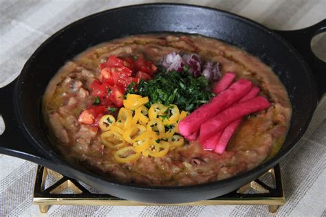 Fotografía de un plato de Foul Mudammas con sus tradicionales decoraciones de vegetales frescos.