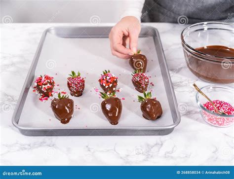 Manos sumergiendo gomitas de colores en chocolate fundido con palillos
