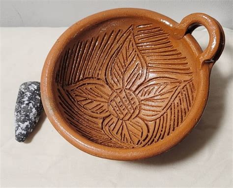 Molcajete de barro lleno de mariscos variados, decorado con aguacate y camarones grandes en el borde.