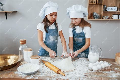 Niños divirtiéndose amasando ingredientes para repostería en una cocina luminosa.