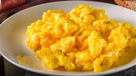 Primer plano de huevos revueltos esponjosos en un plato.