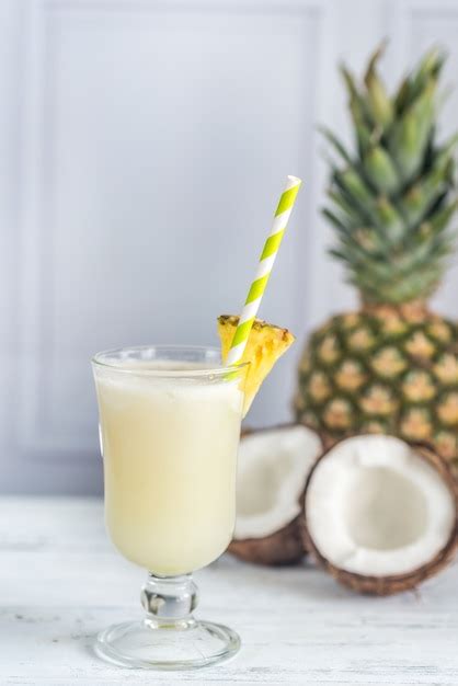 Primer plano de un vaso de Piña Colada adornado con piña y cereza