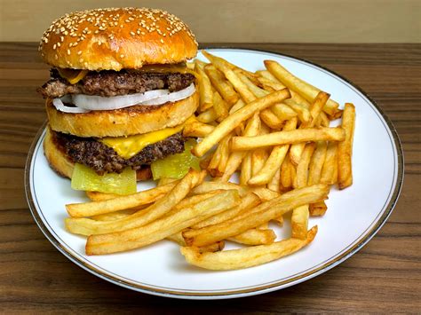 Hamburguesa casera montada con queso, panceta y acompañamiento de papas fritas