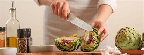 Persona deshojando una alcachofa cocida