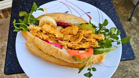 Fotografía de un plato servido con panes con pollo salvadoreños adornados con escabeche fresco.