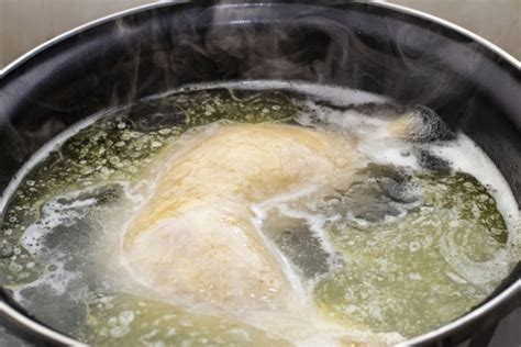 Espuma amarillenta formándose en el caldo de pollo hirviendo