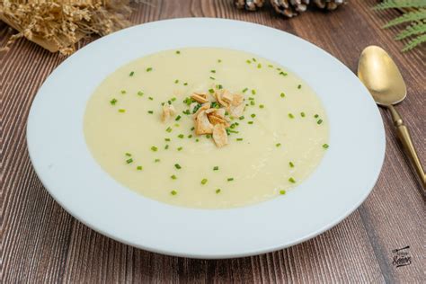 Tazón de crema de espárragos y puerros decorado con hierbas frescas